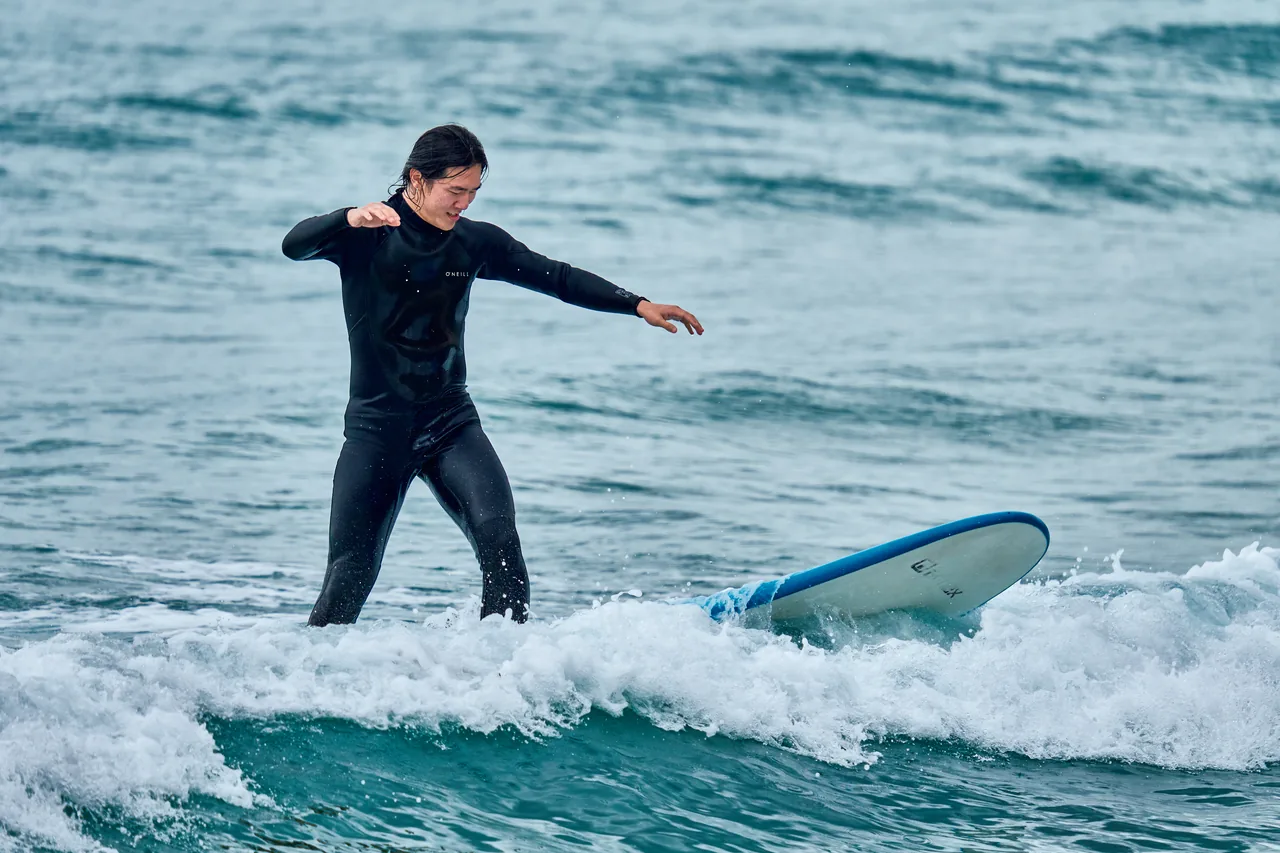 A surfer in a wetsuit riding a small wave at a Korean surf beach