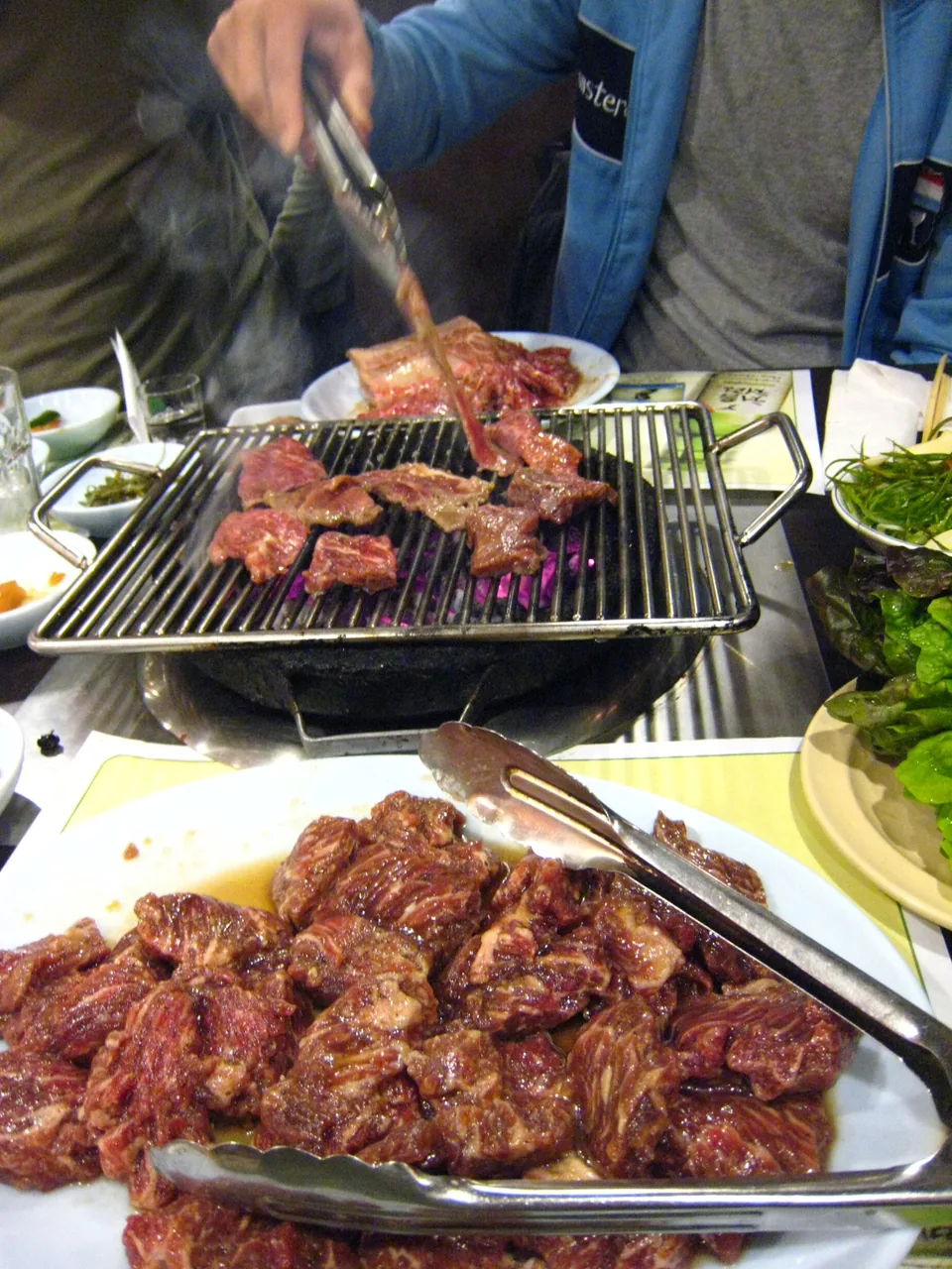 Galbi (beef short ribs) grilling over charcoal at a Korean barbecue restaurant