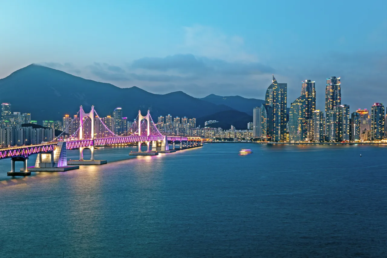 El puente Gwangan y el skyline de Busan iluminados al anochecer sobre la bahía