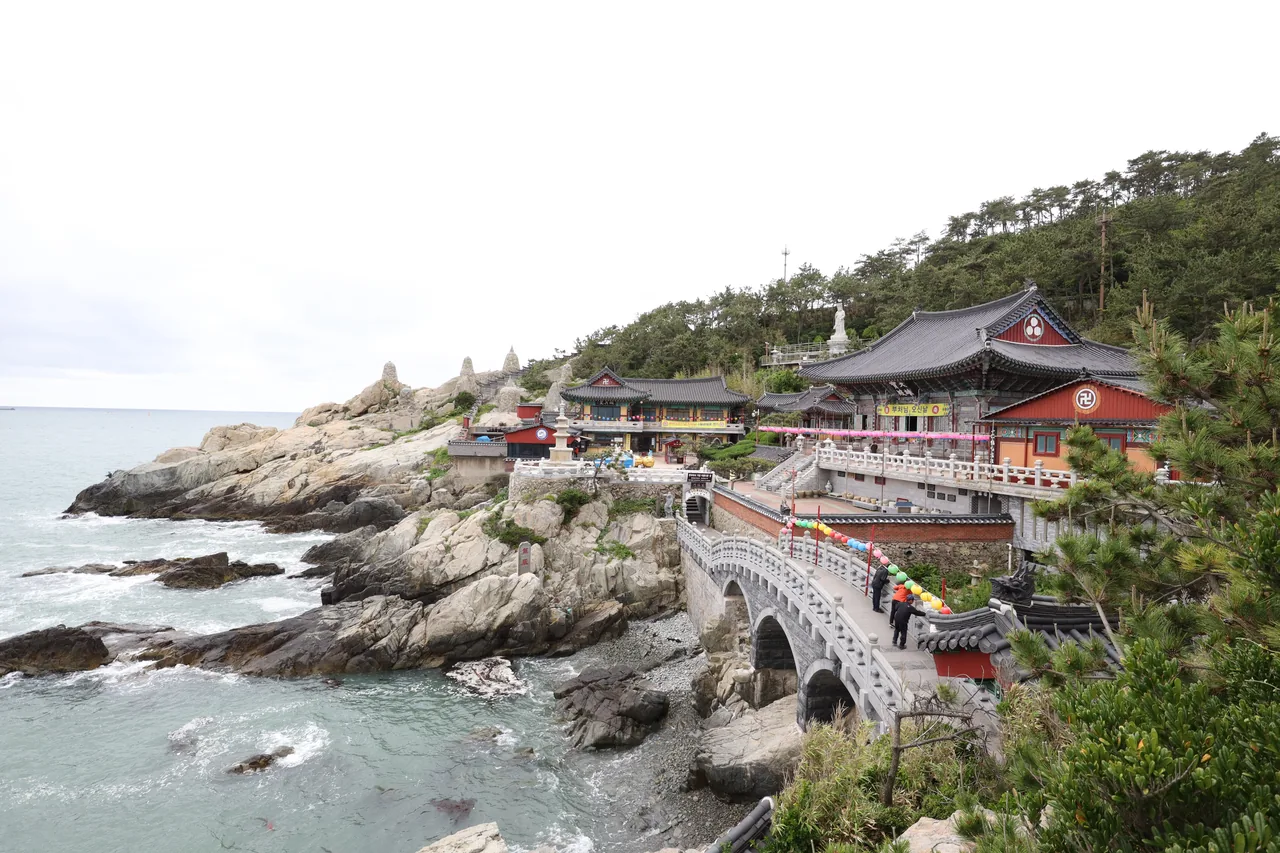 Haedong Yonggungsa Temple with its stone bridge and red-roofed halls on the rocky coast above the sea