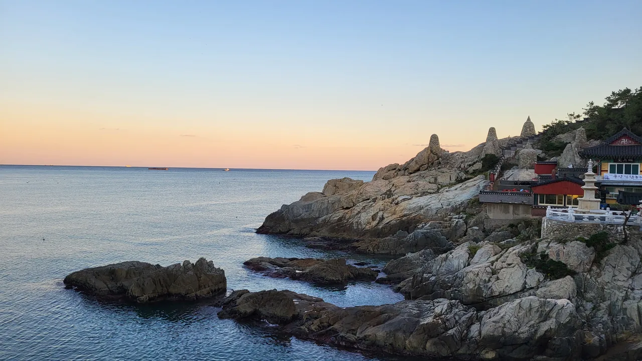 Haedong Yonggungsa temple bathed in golden light at sunset over the sea