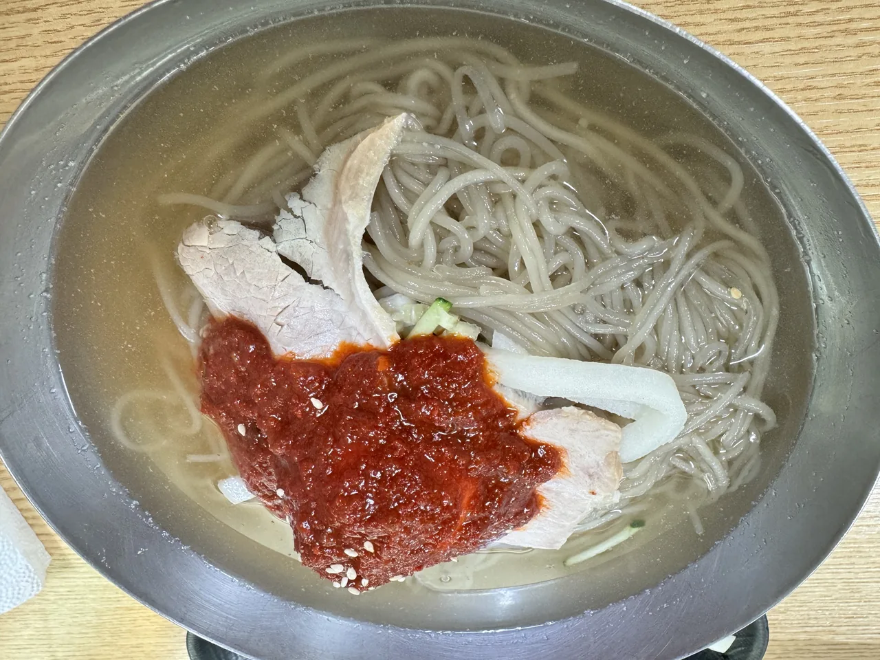 A bowl of mul-milmyeon, Busan's cold wheat noodles in broth with a dollop of red sauce