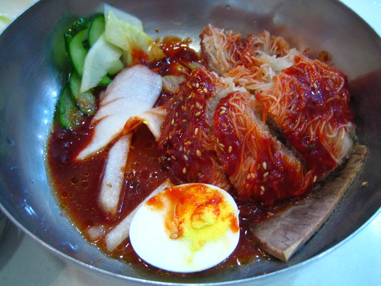 茹で卵をのせた辛い赤タレのビビム冷麺一杯