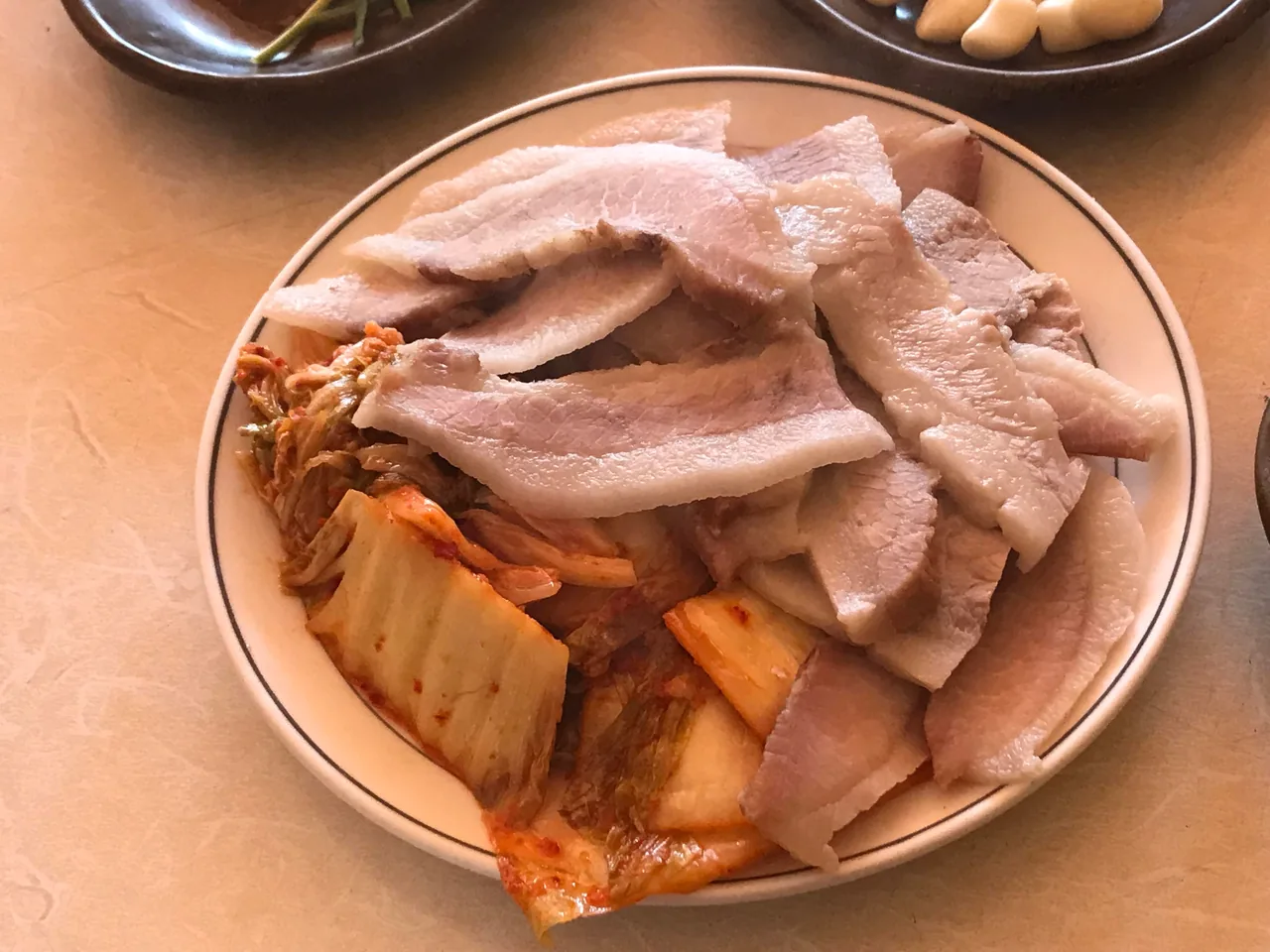 A plate of suyuk, boiled pork slices, served with kimchi
