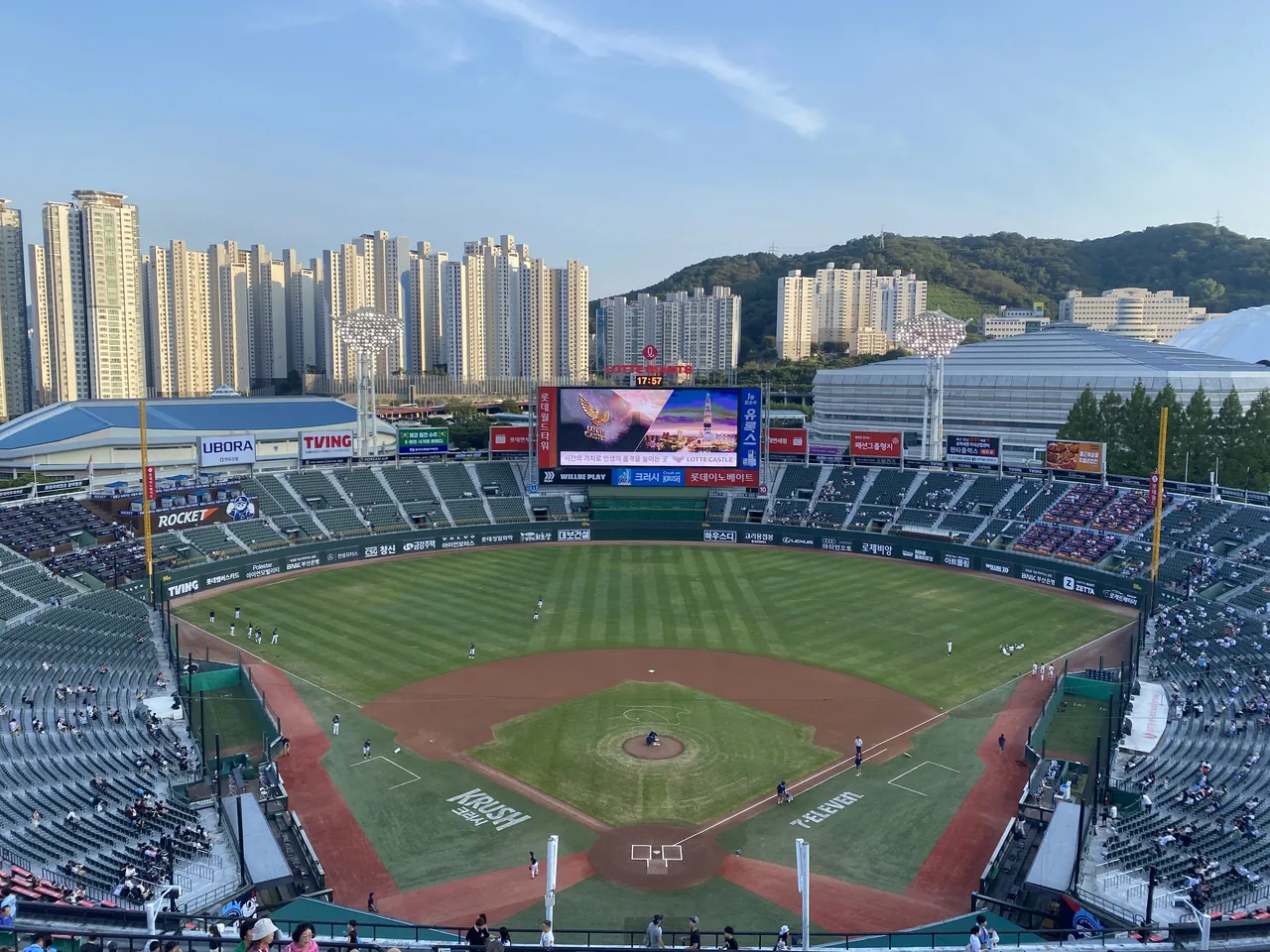 Toàn cảnh mặt sân và khán đài sân Sajik với đường chân trời chung cư Busan phía sau