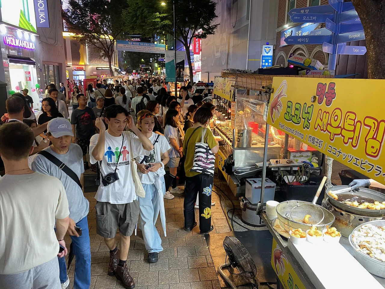 A crowded Myeongdong night street-food market lit by vendor stalls