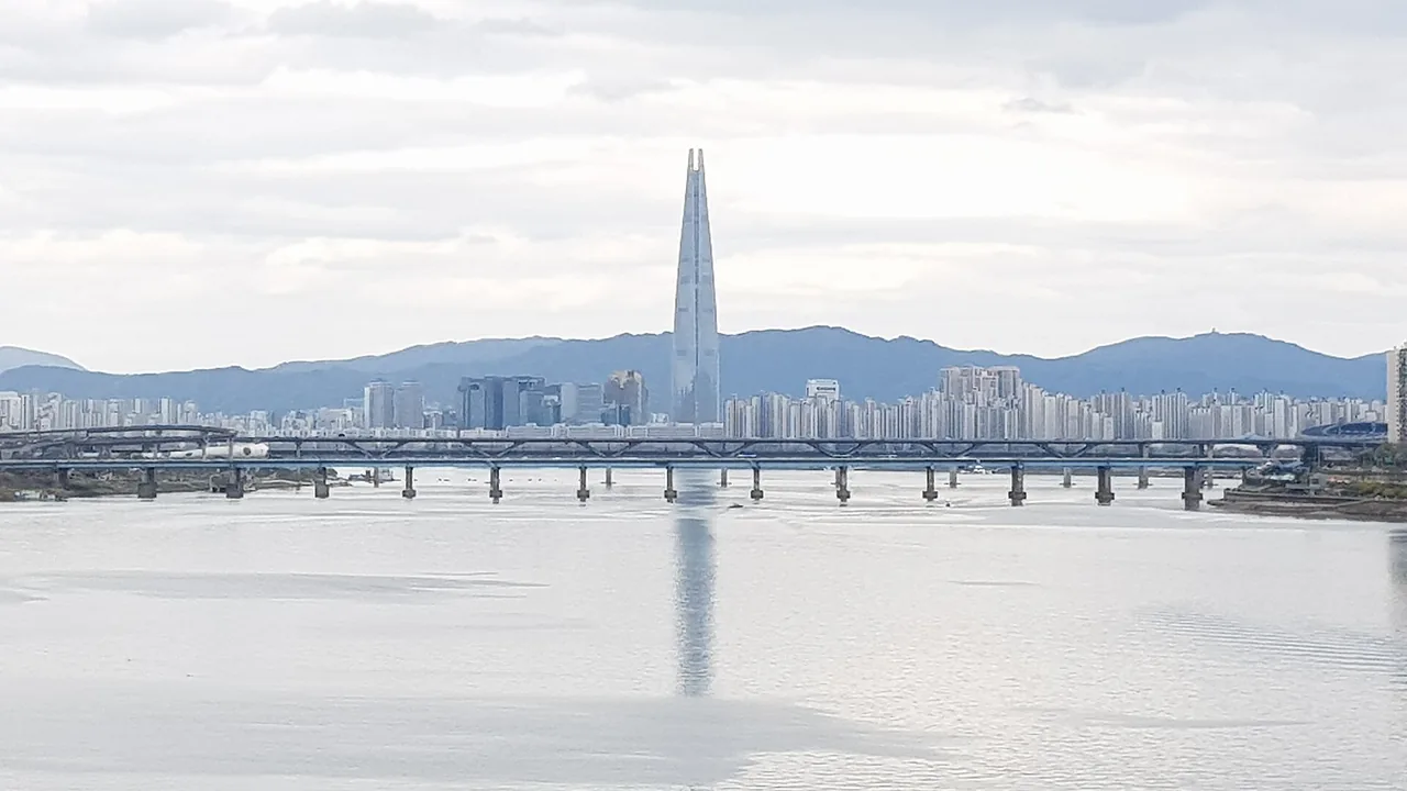 Lotte World Tower rising above the Jamsil skyline and Seokchon Lake at sunset