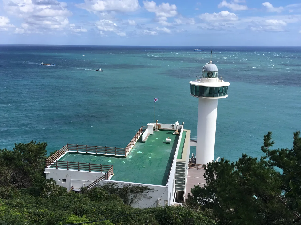 The white Yeongdo Lighthouse and its observation deck above the turquoise sea at Taejongdae in Busan