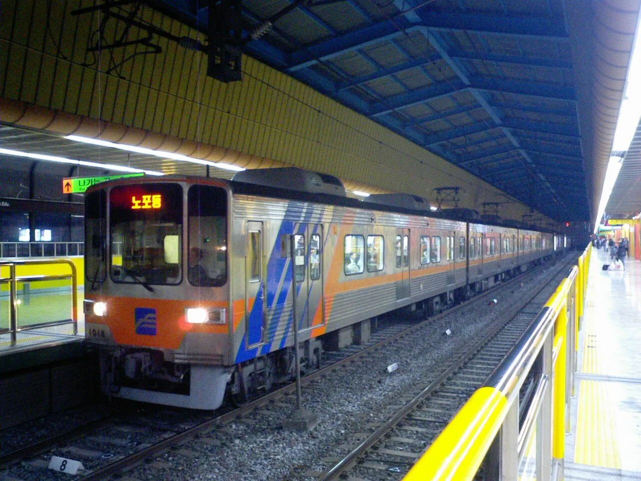 A Busan Metro train at a station platform with English signage