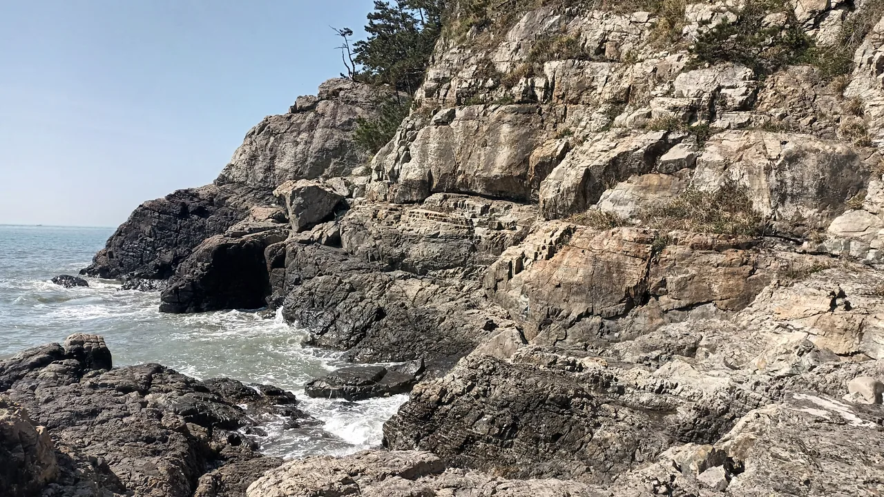 The layered sedimentary cliffs of Molundae dropping straight into the sea at the southern tip of Dadaepo The layered sedimentary cliffs of Molundae dropping straight into the sea at the southern tip of Dadaepo
