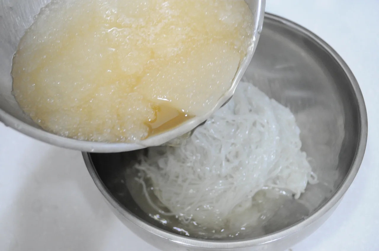 Cold broth being poured over wheat noodles to make mul-milmyeon Cold broth being poured over wheat noodles to make mul-milmyeon
