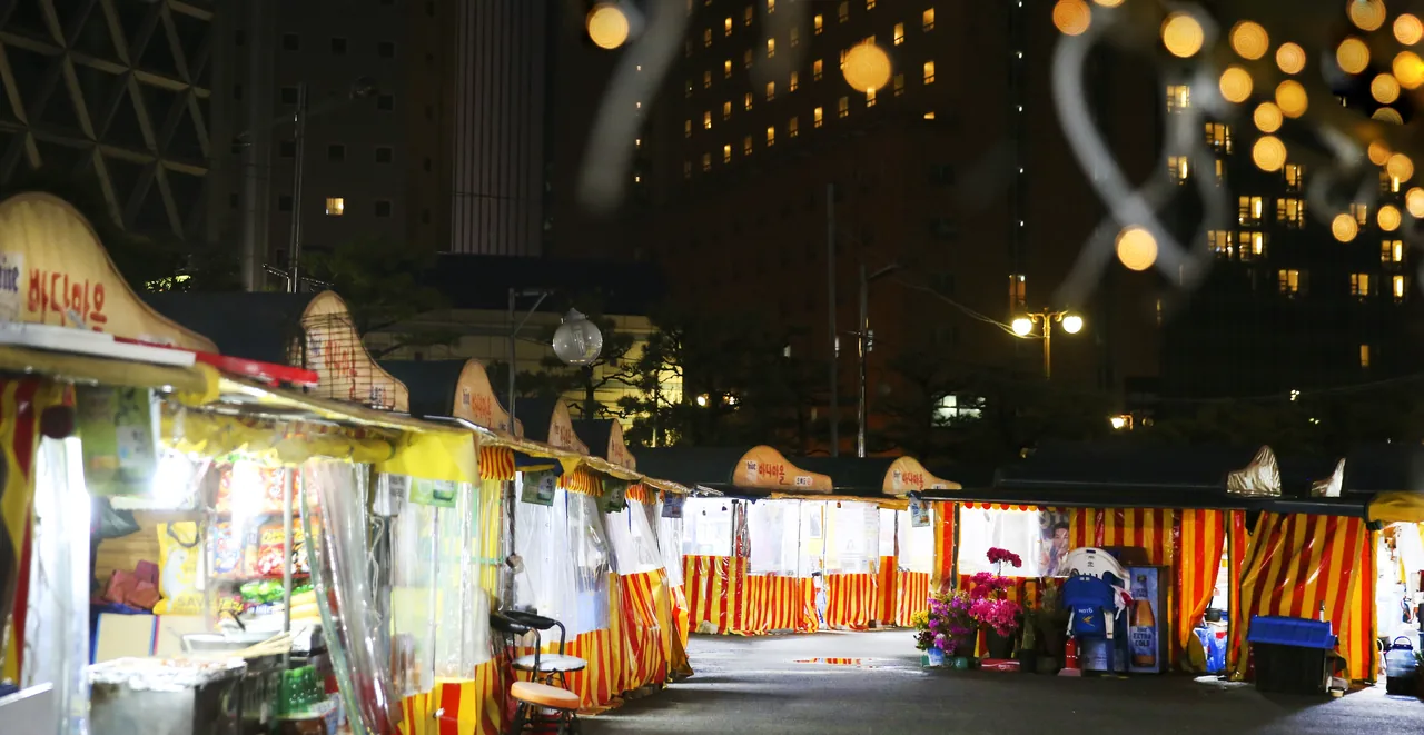 Row of pojangmacha tents in Haeundae with red and yellow striped canopies and a Badamaeul sign