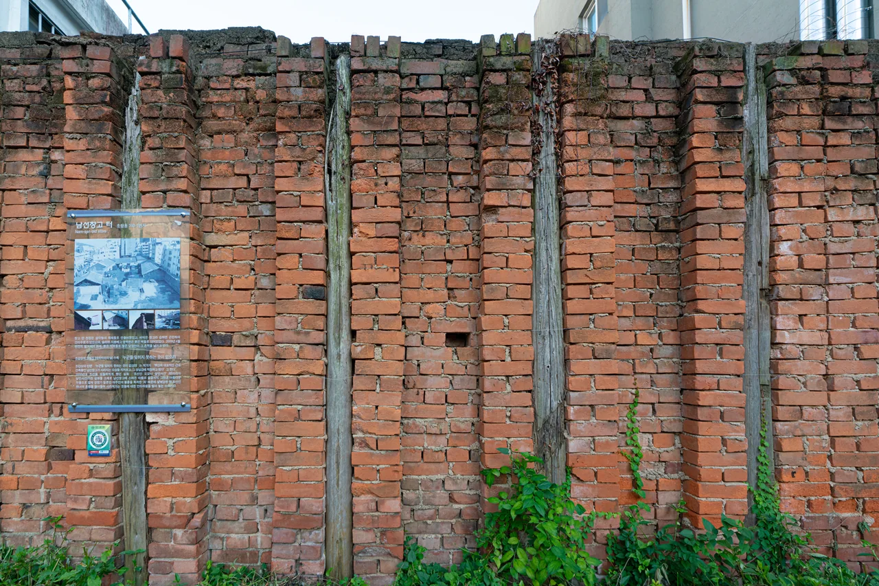 Red brick wall surviving from the Namseon warehouse with an information panel mounted on it