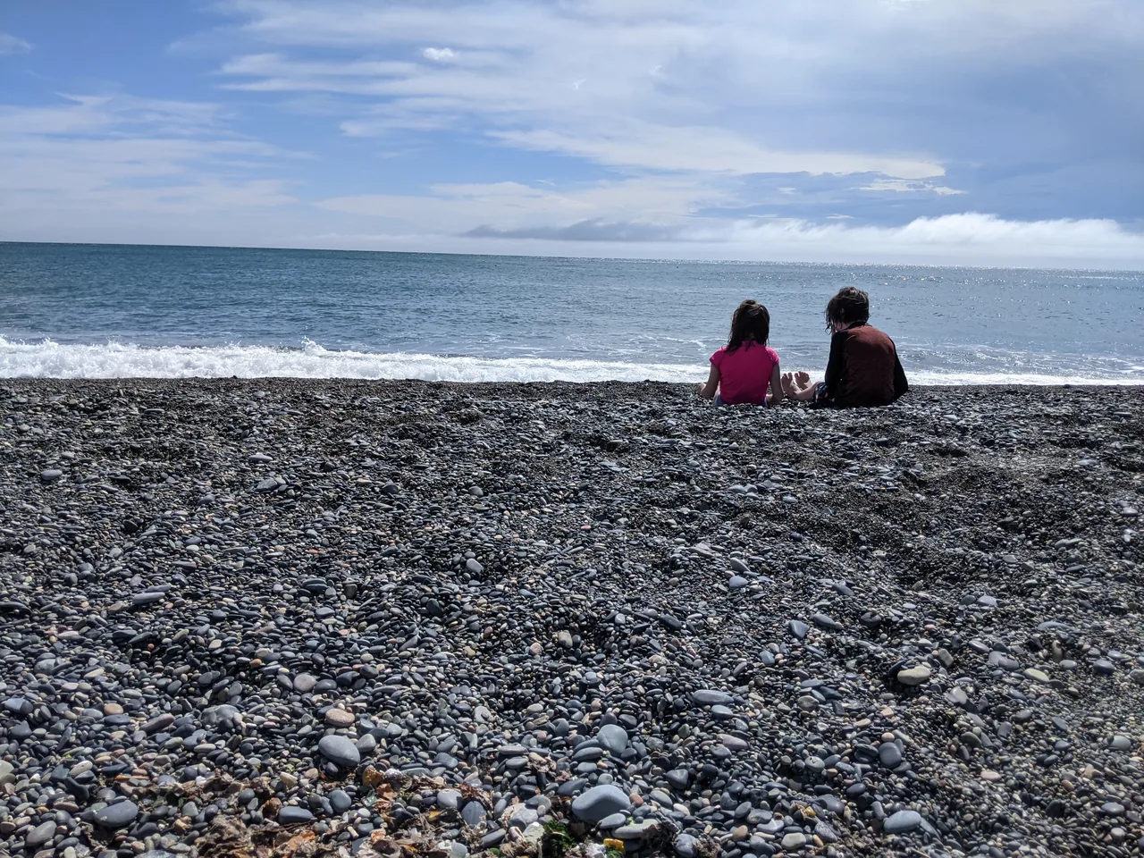 Two children sitting on a pebble beach on Geoje Island