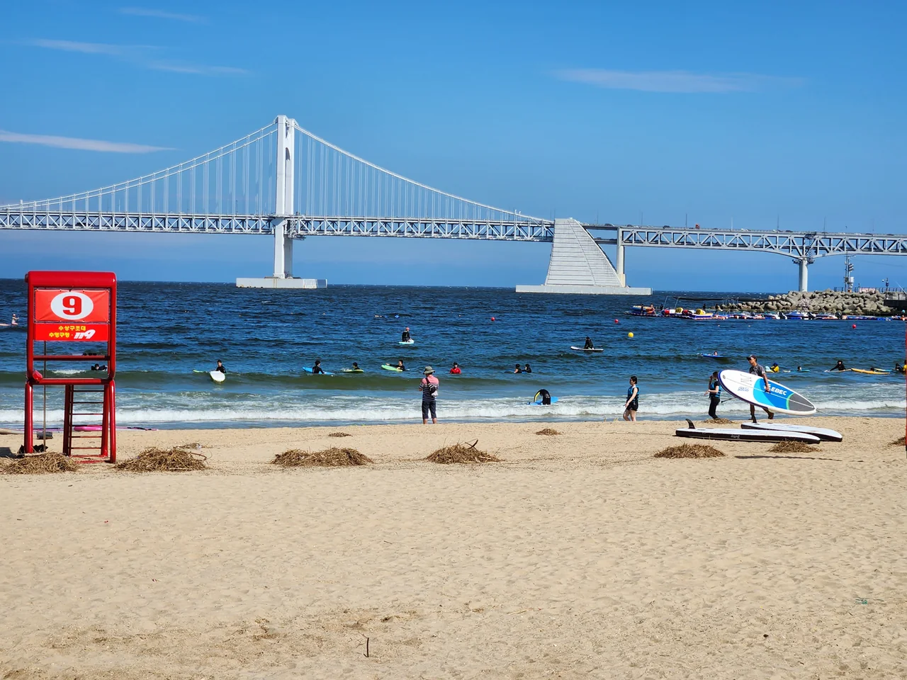 La playa de Gwangalli en verano con surfistas y el puente Gwangan al fondo