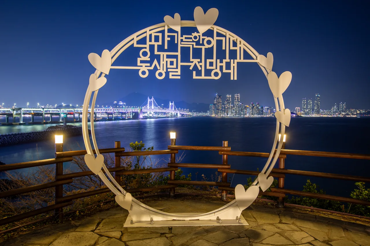 Circular sculpture at the Dongsaengmal viewpoint with the illuminated Gwangan Bridge behind