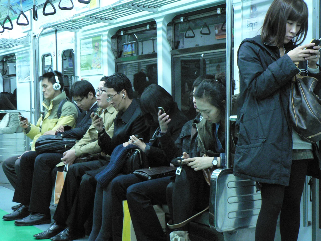 Seated passengers looking at their phones on a Seoul subway train