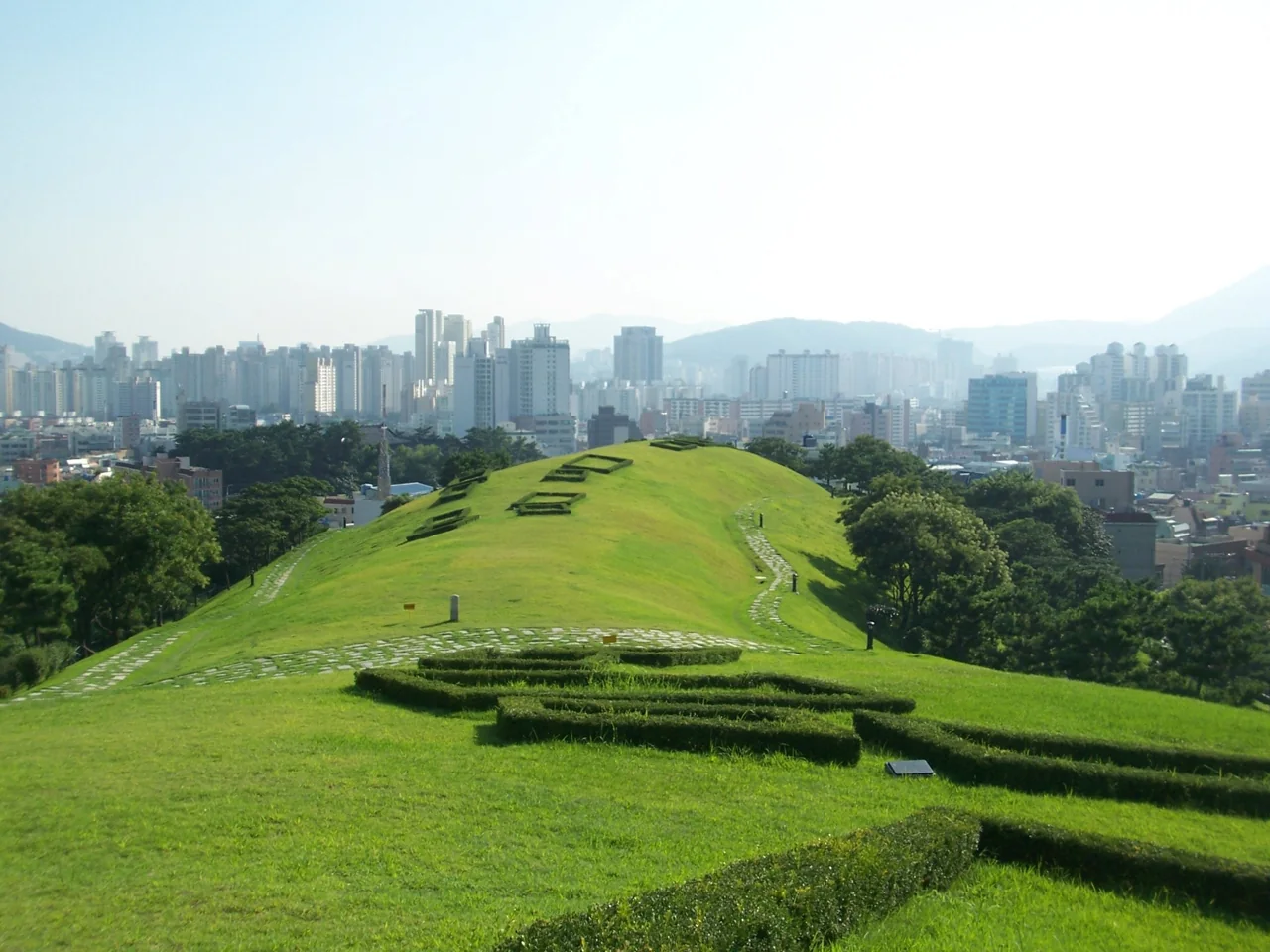 Los túmulos cubiertos de césped de Bokcheon-dong junto al Museo Bokcheon, con Dongnae al fondo