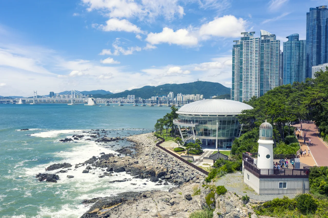 Nurimaru and the lighthouse at the tip of Dongbaekseom, with the Gwangan Bridge beyond