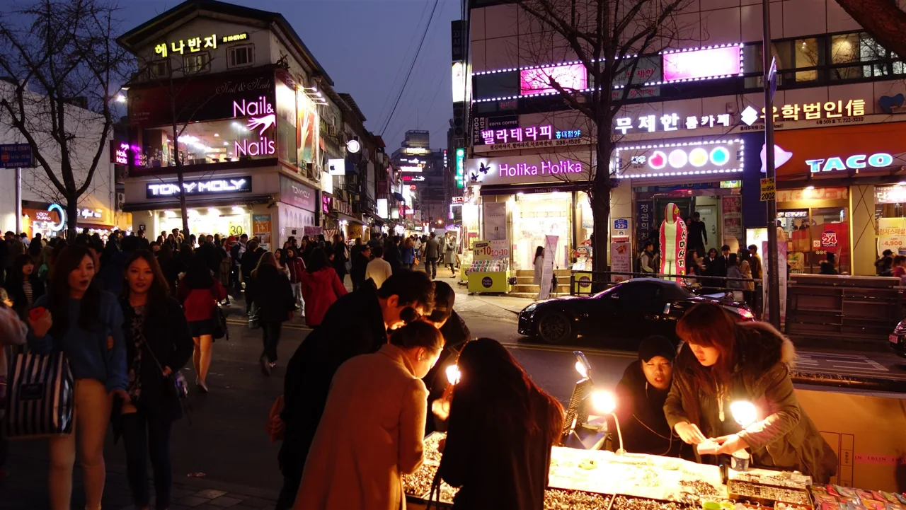 The Hongdae street in Seoul after dark, crowded with people and lit shop signs