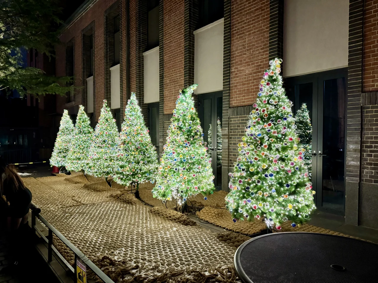 Hileras de árboles de Navidad hechos con bombillas junto a la pared de ladrillo de la catedral de Myeongdong, de noche