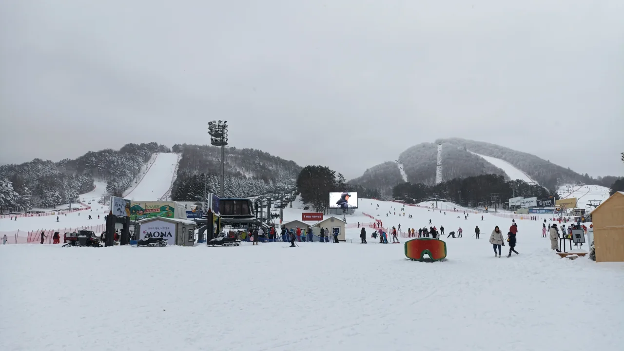 Pistas nevadas, telesillas y esquiadores en la base de la estación de Yongpyong bajo un cielo nublado