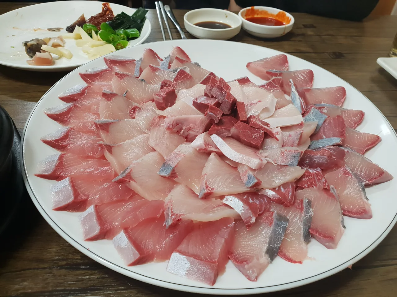 Plato de sashimi de seriola (bangeo) cortado en lonchas gruesas sobre la mesa de un restaurante