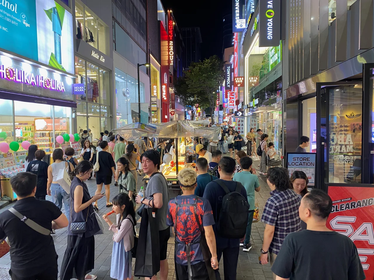 밤의 명동 거리에 늘어선 화장품 매장 간판과 노점