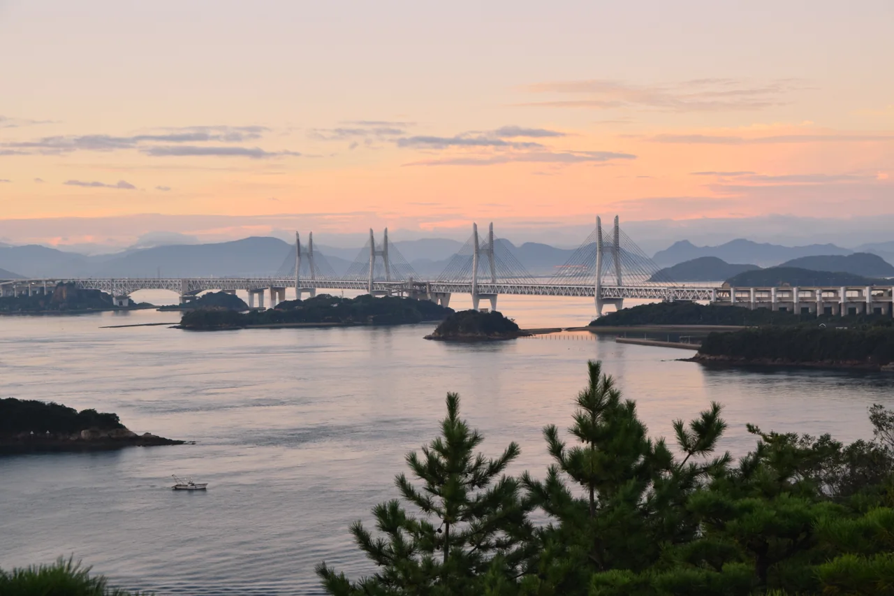 The Seto-Ohashi Bridge spans and small islands of the Seto Inland Sea under a pink dawn sky