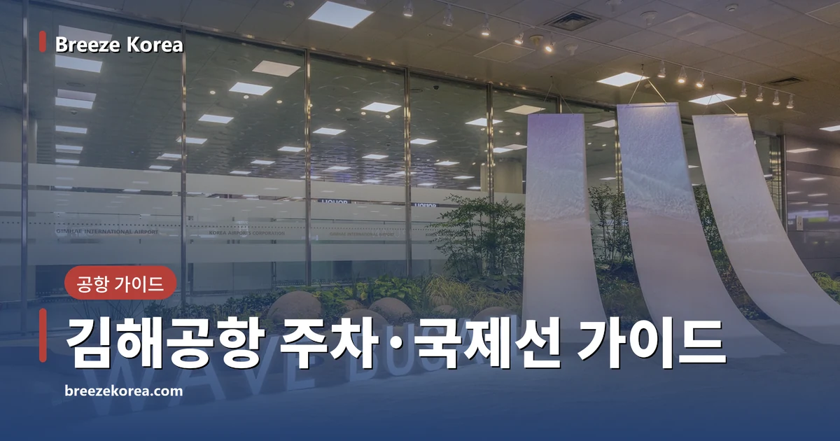 모래를 깐 실내 정원에 켜진 WAVE BUSAN 글자 조명과 흰 천 모양 조형물 세 장, 뒤쪽 유리벽
