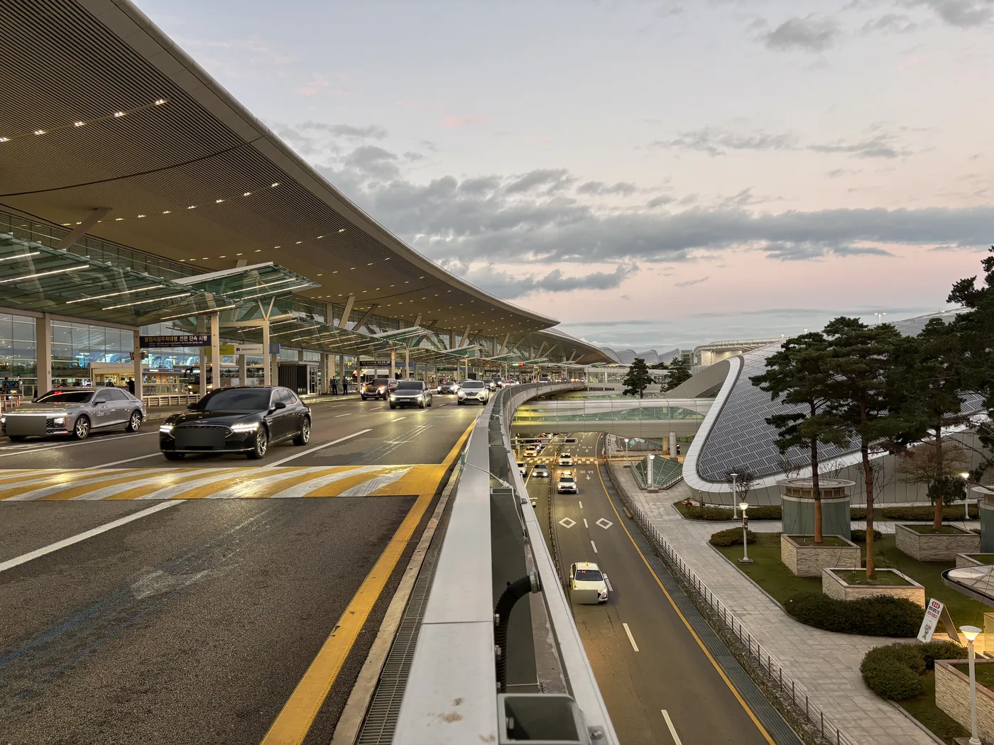 The Terminal 2 departures road at Incheon Airport at dusk, under the long curved roof