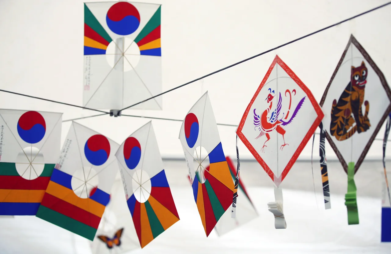 Several traditional Korean kites hanging on a line, painted with taegeuk patterns, a tiger and a phoenix